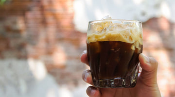 person holding a glass of shaken espresso