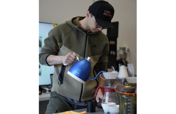 V60 pour-over coffee brewing setup with controlled water pouring during a professional coffee tasting session